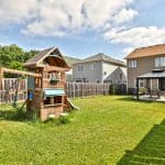 Image of the spacious back yard with s wooden playhouse and a covered picnic table at 6 Warner Lane